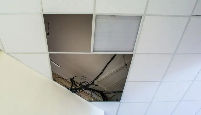 Schema distanza montanti controsoffitto cartongesso: cavi elettrici a vista in un'apertura del controsoffitto modulare.