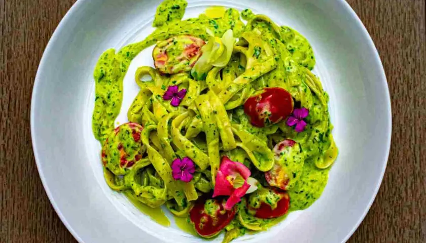 Tagliatelle fresche condite con un cremoso pesto di zucchine, pomodorini e fiori eduli.