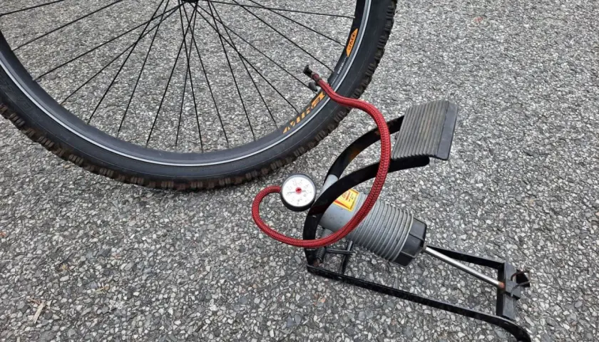 Pompka rowerowa z manometrem obok koła. Sprawdź ciśnienie w oponach rowerowych, tabela pomoże Ci dobrać odpowiednie.