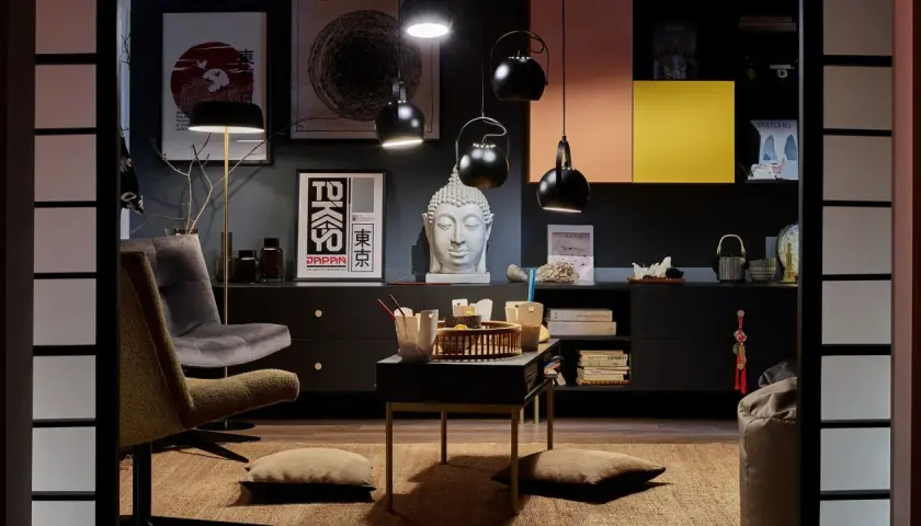 Salon w stylu eklektycznym: szara sofa, fotel, stolik z bambusową tacą, głowa Buddy i plakaty z motywami Japonii.
