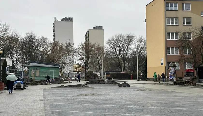 Prace brukarskie w Serbinowie. W tle bloki mieszkalne i zielona budka.
