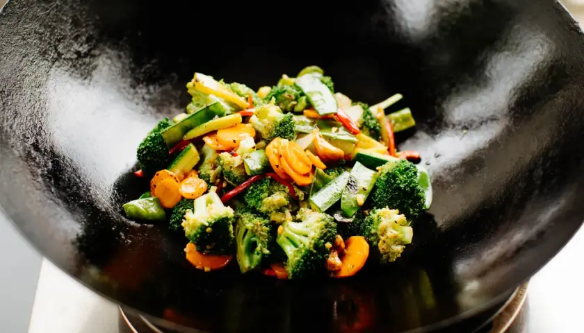 Buntes Gemüse (Brokkoli, Karotten, Zucchini) wird in einer Wokpfanne zubereitet. Ein schnelles und gesundes wok pfanne rezept.