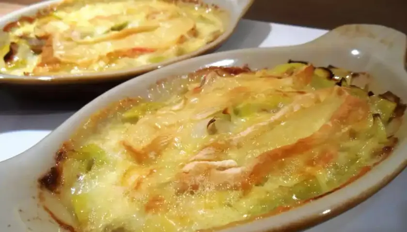 Gratin de poireaux au reblochon, fondant et doré, servi dans des ramequins individuels. Un délice réconfortant.