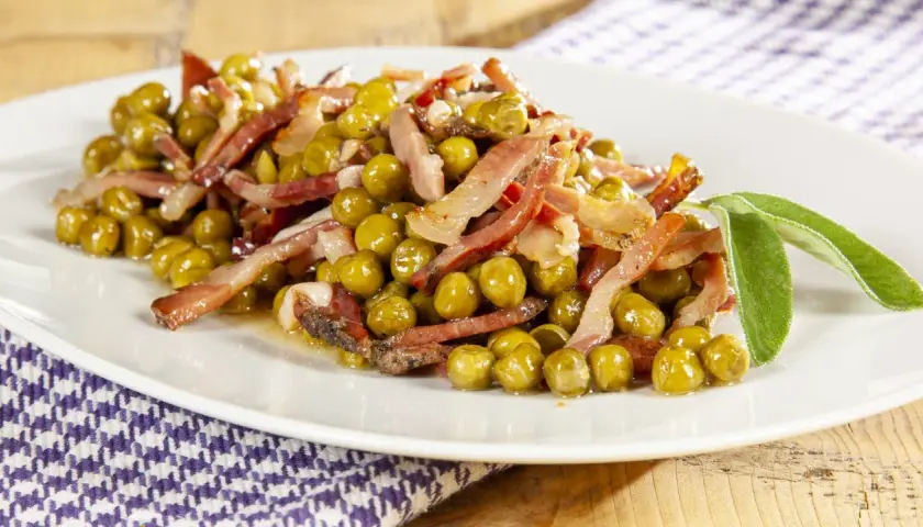 Un piatto invitante di piselli e pancetta croccante, guarnito con foglie di salvia fresca. Un classico sapore italiano.