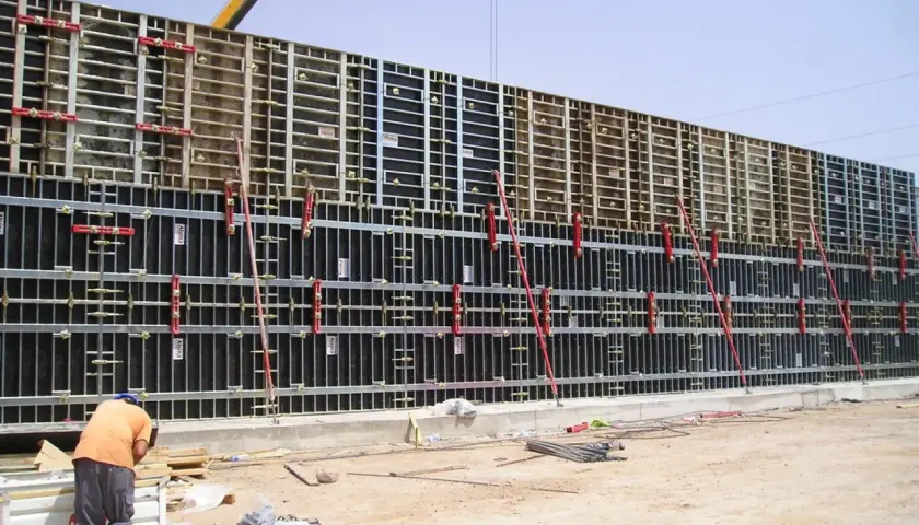 Un ouvrier travaille sur un grand petit coffrage béton, prêt pour le coulage. La structure métallique est impressionnante.