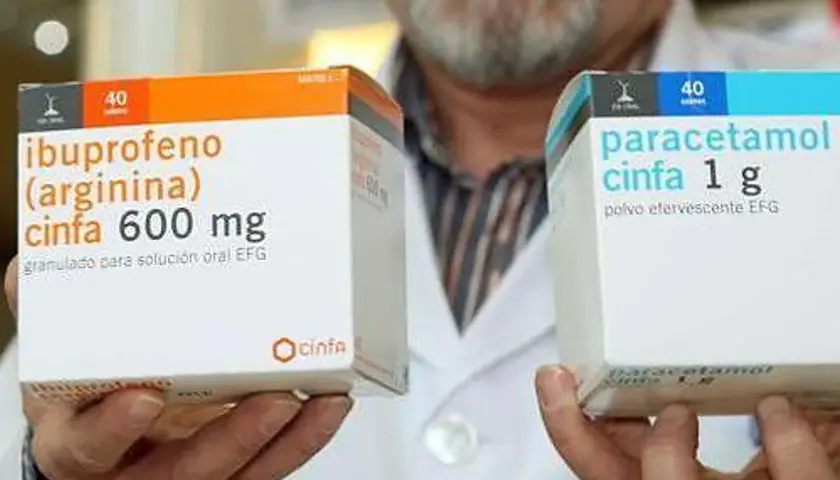 Manos sostienen cajas de medicamentos. Una caja muestra "ibuprofeno cinfa 600 mg" y la otra "paracetamol cinfa 1 g". Ambos son para la fiebre paracetamol o ibuprofeno.