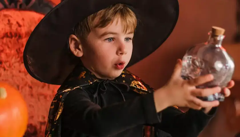 Niño mago con sombrero y capa, sosteniendo una botella con forma de calavera. ¡Perfecto para trucos de magia para niños de 3 a 6 años!