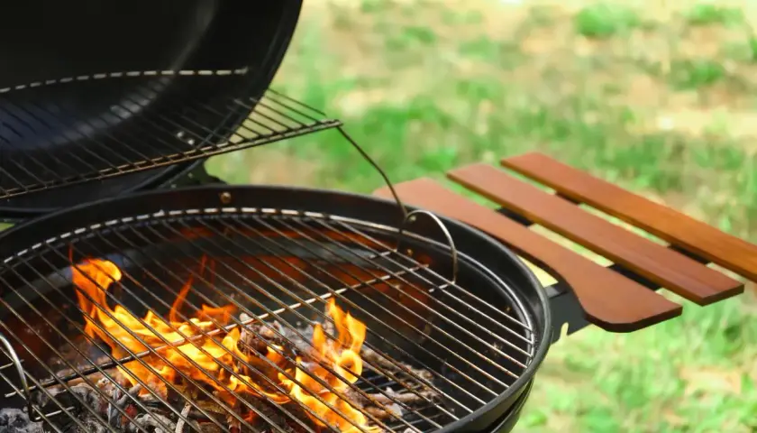 Un barbecue prêt à l'emploi, les flammes montent, signalant la bonne température bbq pour un repas en plein air.
