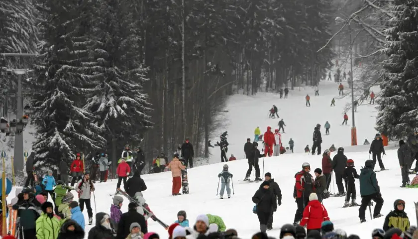 Tłumy narciarzy i snowboardzistów na stoku, przygotowujących się do szusowania. Wszyscy cieszą się zimową atmosferą, jakby to były ich wymarzone ferie 2027.