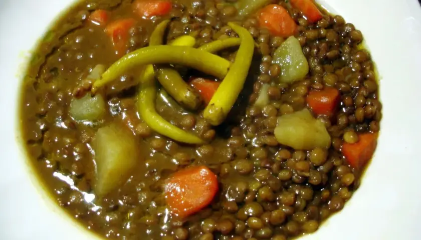 Un plato de lentejas con verduras, patatas y guindillas verdes. Un guiso reconfortante y nutritivo.