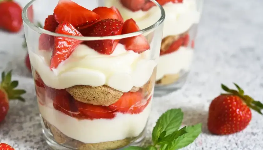 Un délicieux dessert léger aux fraises, alternant biscuits, crème onctueuse et fruits rouges frais, servi dans des verres.