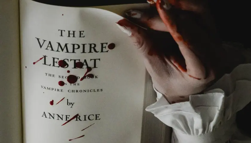 Książki o wampirach dla młodzieży, jak "Wampir Lestat" Anne Rice, z krwawymi śladami na stronach i dłoni.