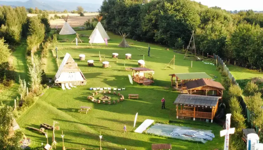 Wioska indiańska w Lubelskiem z tipi, drewnianymi chatkami i miejscem na ognisko.