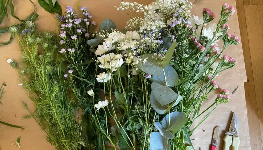 Un assortiment de feuillage pour bouquet, prêt à être assemblé. Des fleurs blanches, roses et violettes se mêlent à des feuilles d'eucalyptus.