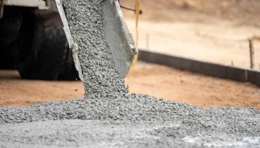 Gruszka betonu z betoniarki wysypuje się na plac budowy. Trudno ocenić ile m3 betonu jest wylewane.
