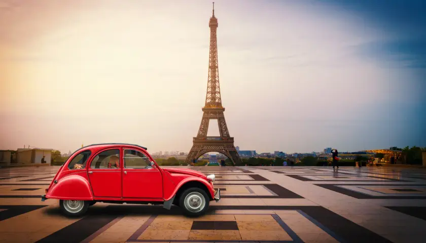 Czerwony Citroën 2CV na tle Wieży Eiffla w Paryżu.