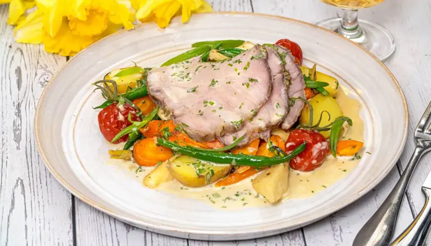 Skinkstek i ugn serverad med rotfrukter, gröna bönor och en krämig sås. En härlig vårmåltid.