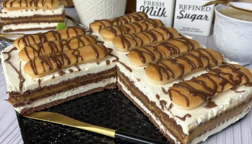Pyszne ciasto z kajmakiem i mascarpone, udekorowane biszkoptami i czekoladą. Idealne na deser.