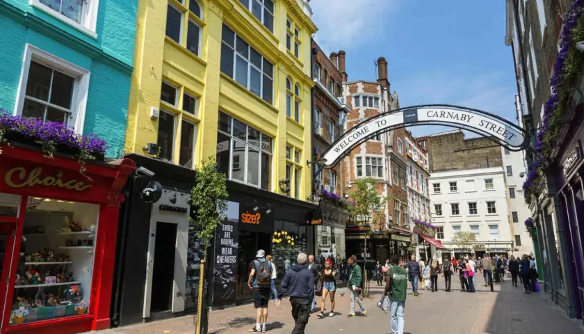 Kolorowe fasady sklepów i łuk z napisem "Welcome to Carnaby Street" zapraszają do tętniącej życiem ulicy pełnej ludzi.