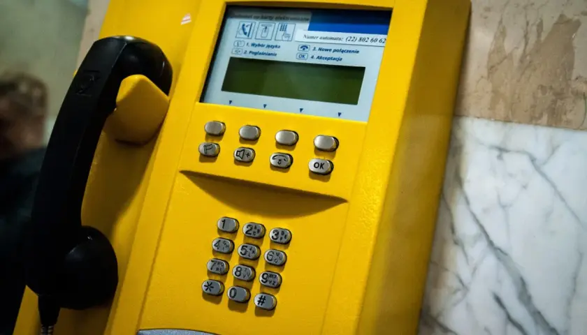 Żółta budka telefoniczna z numerem kierunkowy 94. Słuchawka czeka na połączenie.