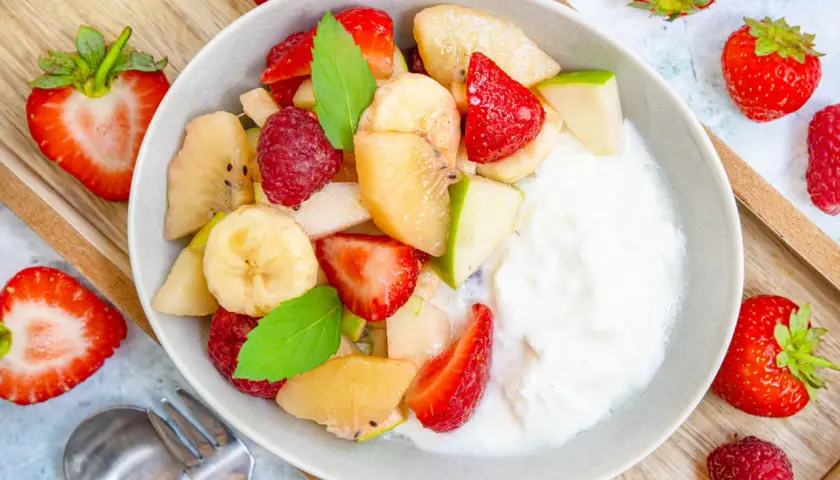 Frischer Obstsalat mit Joghurt, Erdbeeren, Bananen, Äpfeln und Himbeeren. Ein einfaches obstsalat rezept für jeden Tag.