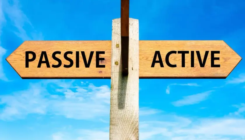 Cartello stradale con frecce "PASSIVE" e "ACTIVE" sotto un cielo azzurro. La scelta tra essere passivi o attivi è presentata.