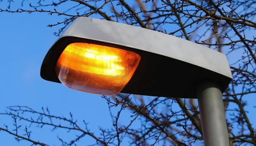 Pomarańczowa lampa uliczna świeci jasno, mimo że jest dzień. Awaria oświetlenia ulicznego?