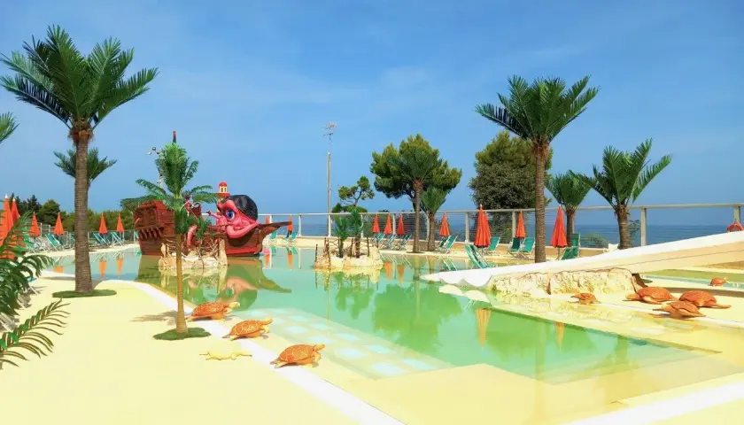 Villaggi Marche sul mare per bambini: piscina con nave pirata, palme e tartarughe. Ideale per vacanze spensierate.