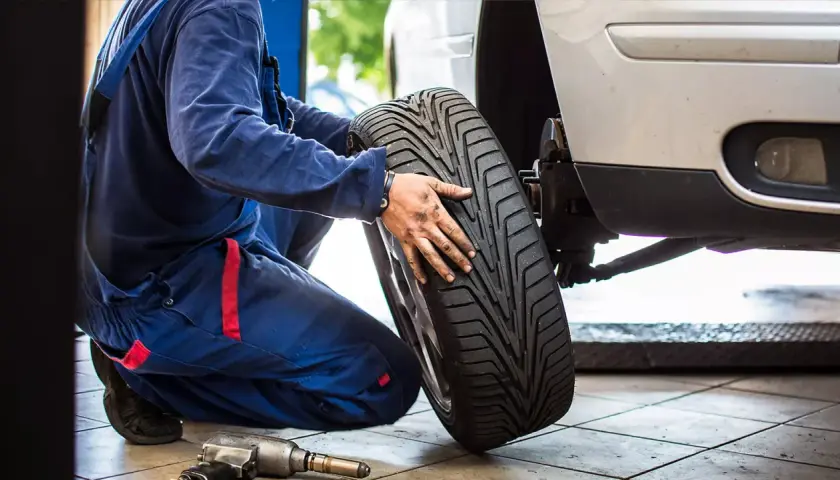 Mechanik wymienia oponę w Toyocie Yaris. Sprawdza rozmiar opon przed montażem.