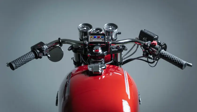 Manubrio di una moto custom rossa con specchietti, tachimetro e contagiri.