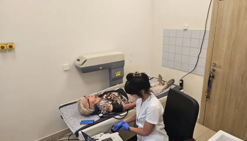Pacjentka leży na łóżku podczas próby tężyczkowej. Pielęgniarka monitoruje jej stan.