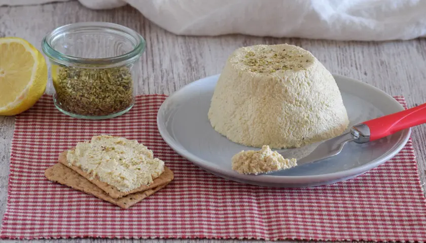 Deliciosa ricotta vegana con hierbas, servida en un plato con galletas y limón.