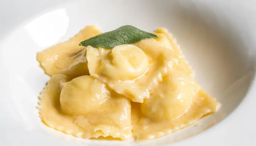 Ravioli dorati in salsa cremosa, guarniti con una foglia di salvia. Il ripieno per ravioli è un segreto gustoso.