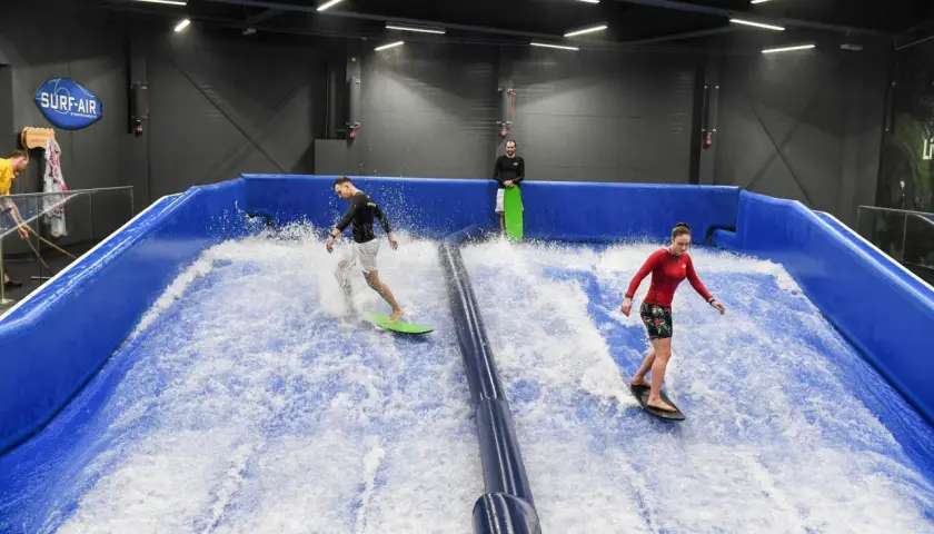 Ludzie surfują na sztucznej fali w Surf-Air, największym aquaparku w Polsce.