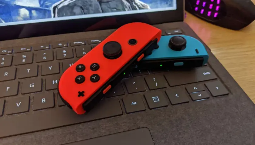 Czerwony i niebieski Joy-Con na klawiaturze laptopa, gotowe do gry. Dowiedz się, jak podłączyć Nintendo do komputera.