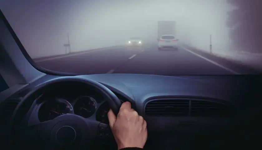 Conduciendo en carretera con poca visibilidad por niebla. Hay poca visibilidad por niebla, ¿qué debe hacer? Reducir velocidad y usar luces antiniebla.