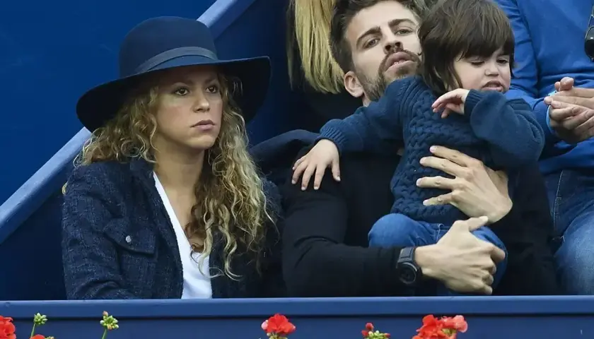 Shakira i Pique oglądają mecz, siedząc obok siebie. Pique trzyma na rękach dziecko.