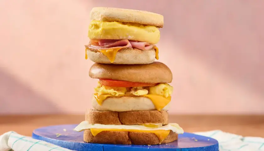Une pile de sandwichs gourmands, parfaits pour une recette de petit-déjeuner. Œufs brouillés, fromage fondant, jambon et tomate.