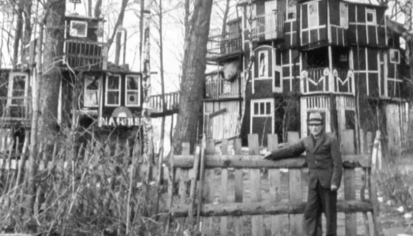 Staffan Lamm vid ett fantasifullt trädkojehus med flera våningar och fönster.