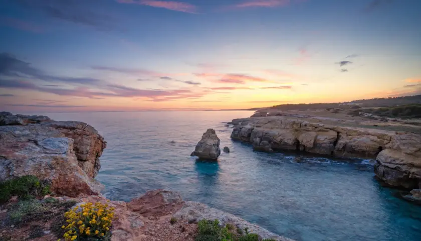 Sonnenuntergang an Menorcas Küste. Felsen, türkises Wasser und ein pastellfarbener Himmel – perfekte Menorca Urlaub Tipps für Romantiker.