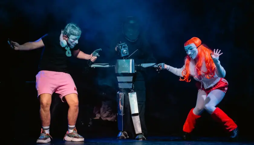 Na scenie Opolskiego Teatru Lalki i Aktora trzej artyści w maskach, jeden z nich steruje robotem.