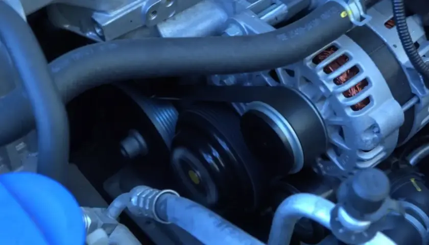 La correa de distribución se ve girando en el motor, conectando el alternador y otras poleas.