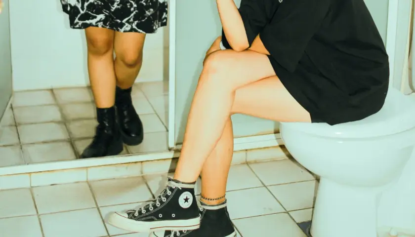 Dwie kobiety w łazience. Jedna siedzi na toalecie, druga stoi obok. Po seksie czas na higienę.