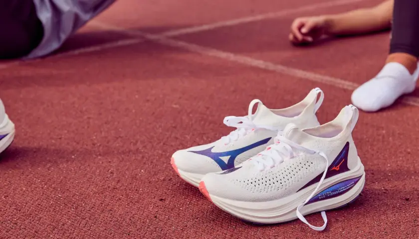Białe buty do biegania Mizuno Neo Vista 2 z niebieskimi akcentami na bieżni.
