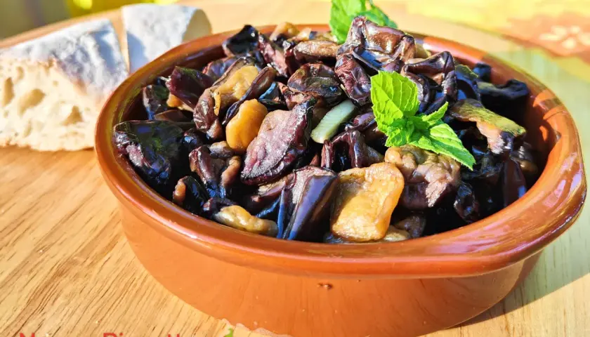 Melanzane alla scapece in terracotta, guarnite con menta fresca, accanto a pane casereccio. Un piatto estivo che profuma di tradizione.