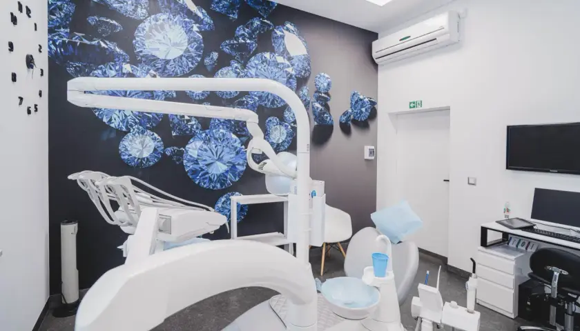 Nowoczesny gabinet stomatologiczny z fotelem dentystycznym i tapetą z niebieskimi diamentami.