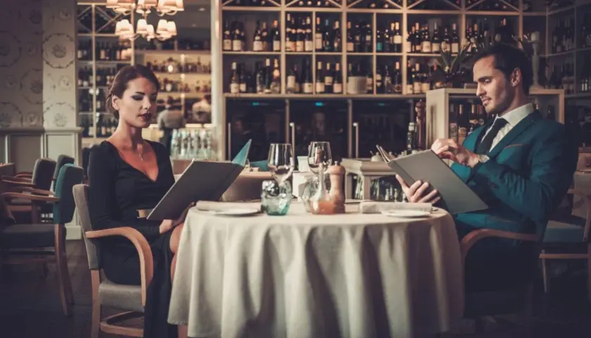 Elegancka para przy stoliku w restauracji, przeglądająca karty dań. Krótki dialog w restauracji po angielsku w tle.