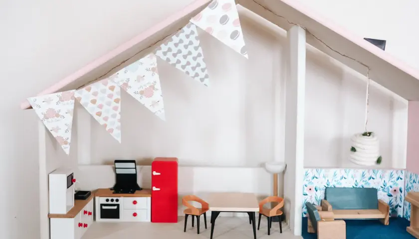 Uroczy domek dla lalek DIY z kuchnią, jadalnią i salonem. Girlanda z makaroników dodaje mu uroku.