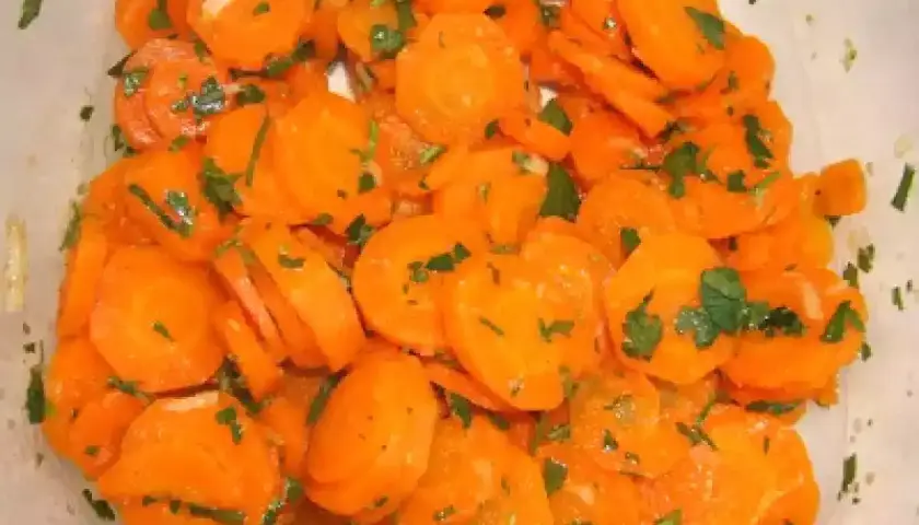 Una deliciosa ensalada de zanahoria cortada en rodajas finas y aderezada con perejil fresco.