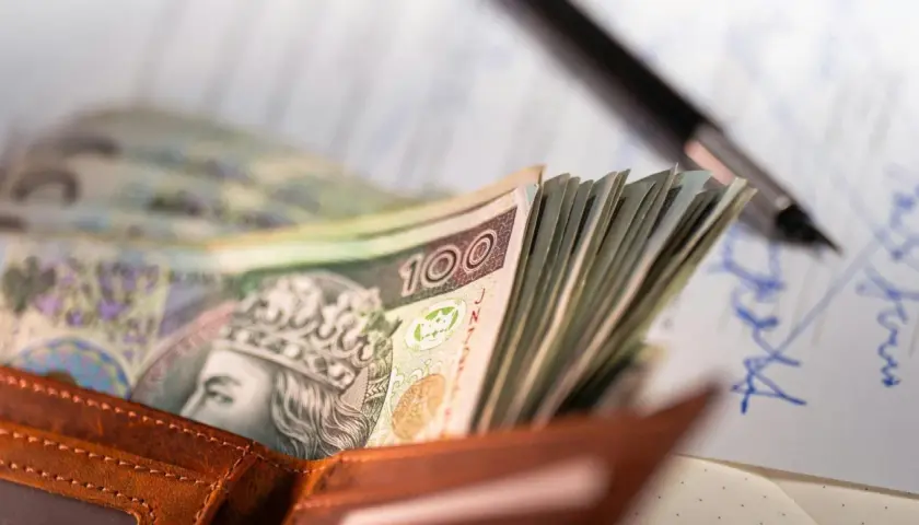 Portfel z polskimi banknotami 100 zł, długopis i dokumenty.